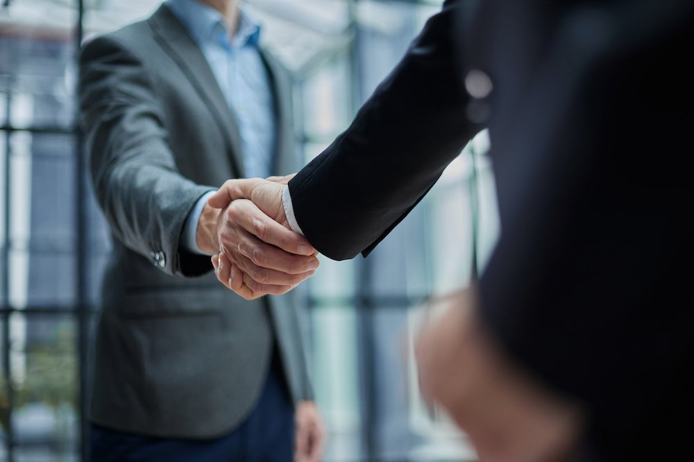 Two business development managers in suits shaking hands.