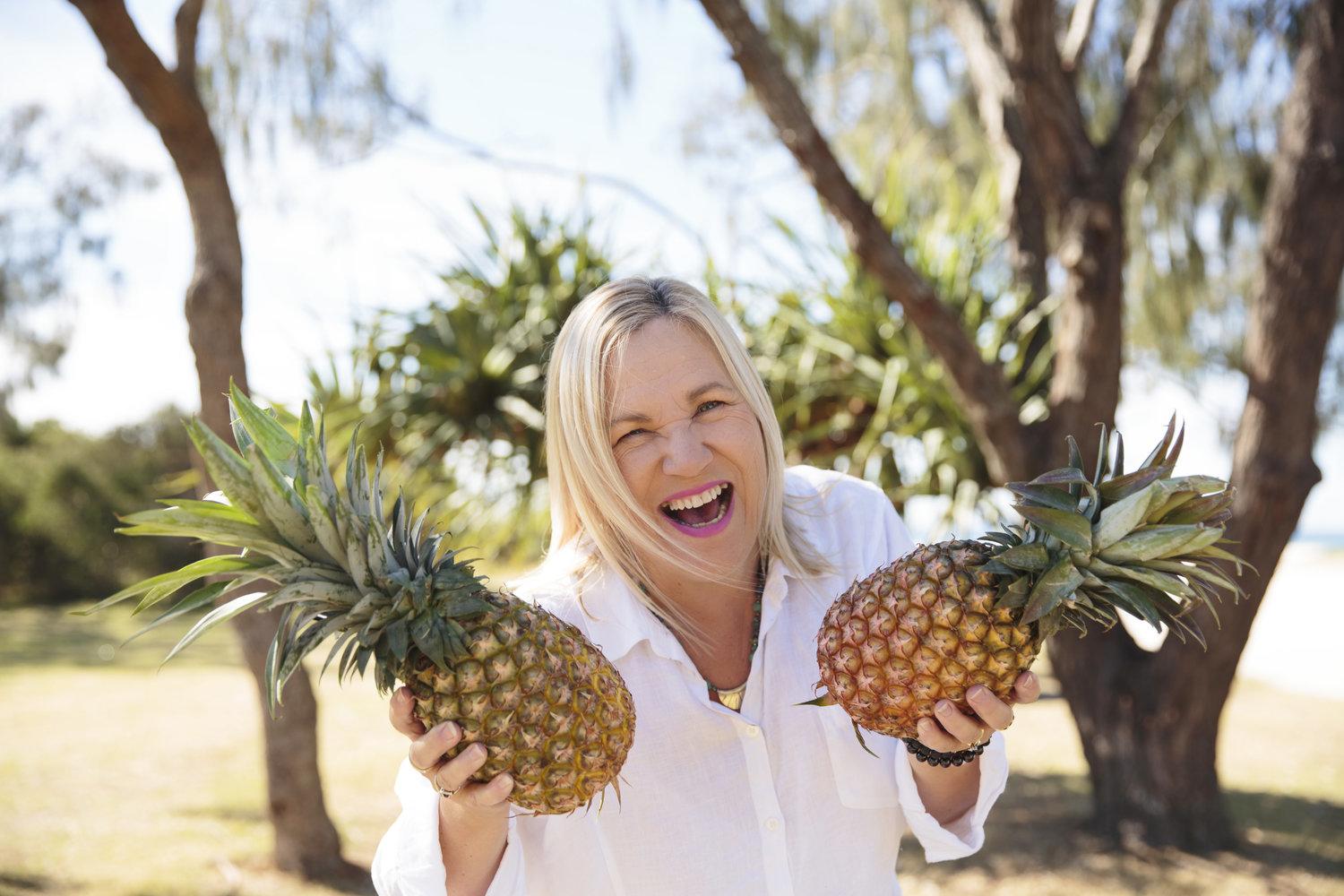 Dianne Doyle holding two pineapples and smiling at the camera