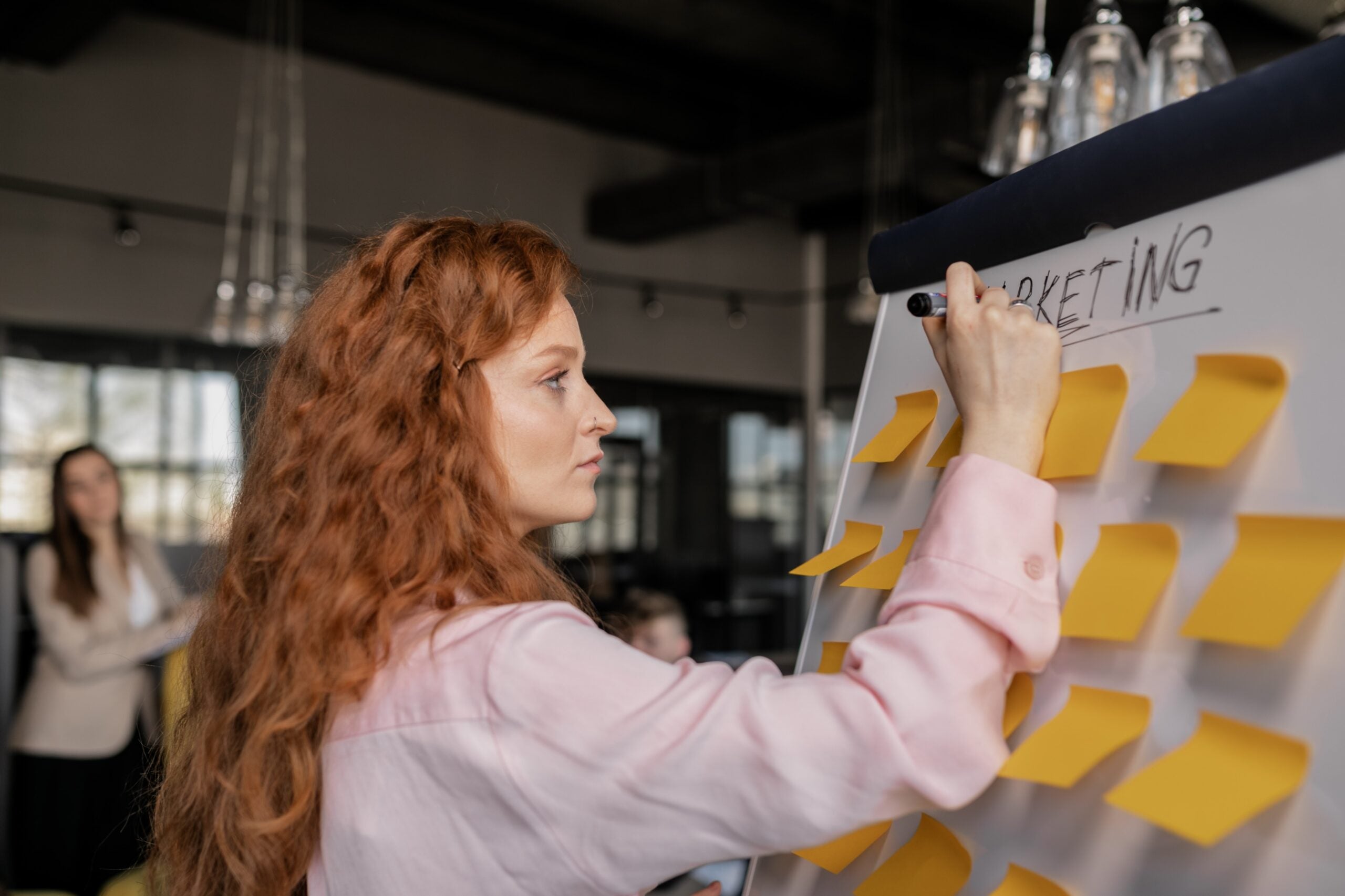 woman working in marketing, writing on a whiteboard